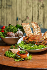 grilled crab with vegetables and sauce on a wooden table in a restaurant