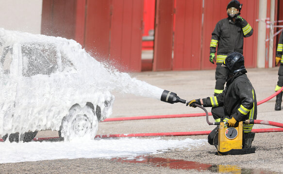 firefighters putting out the car fire after the terrible road accident with white foam