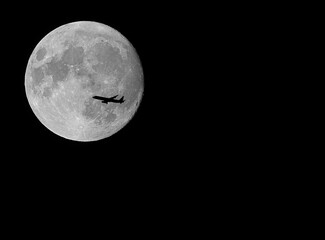 giant super moon and silhouette of the plane flying high in the black sky