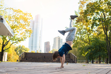 child, teenager dancing in a park in the city. An 11 year old boy is doing breakdancing outside on...