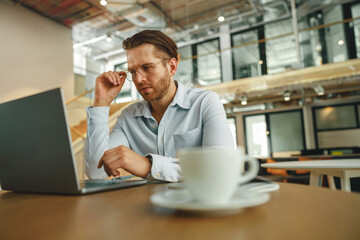 Fototapeta na wymiar Busy sales manager drinking coffee during working on laptop in modern office . High quality photo