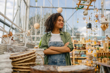 Smiling female garden shop seller standing on flower store background. Gardening concept