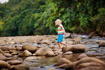 Child hiking in mountains. Kids at river shore.