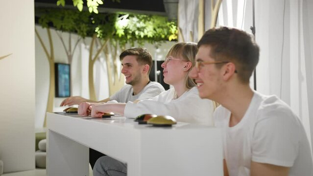 Three friends, teenagers having fun playing a quiz game visiting an amusing interactive natural history museum, handheld shot. Education and entertainment concepts.