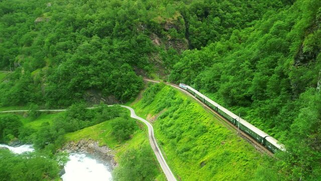Aerial drone Norway landscape. Flamsbana train on Flam Railway. Mountains and waterfalls of Norway in summer. Famous train adventure for cruise ship tourists in Flam. 