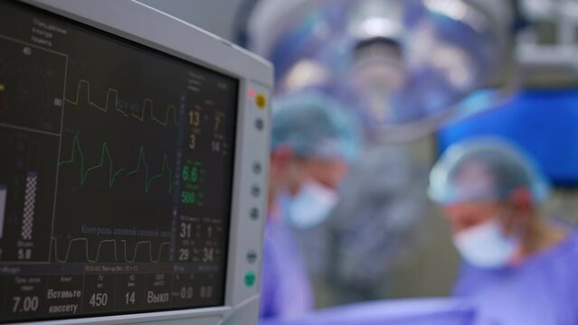 Patient's life signs on the screen of monitor. Lung ventilator machine working during operation. Close up.