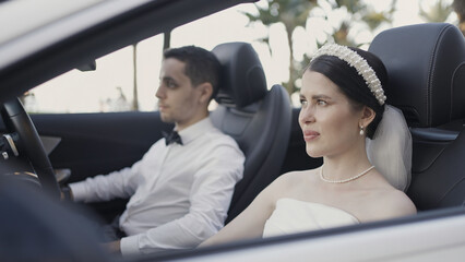 Beautiful couple in convertible. Action. Beautiful couple in festive elegant outfits in car. Couple...