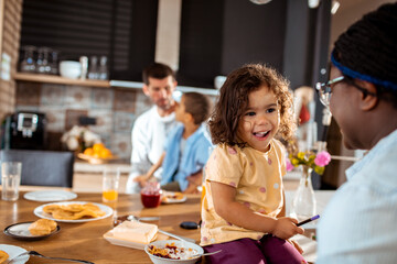 Young mixed mother and daughter drawing and having fun in the kitchen at home