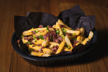 Freshly cooked cheese fries served on a wooden table