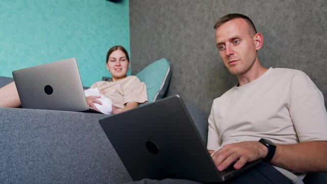 Caucasian Man Looks Intently On Laptop Screen. Working First Time Parents Combining Work And Baby Care.