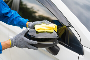 close-up shot of a hand wiping a car's windshield with yellow microfiber cloth, mechanic's hand...