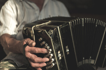 Aged male with white shirt and a wrinkled hand playing on bandoneon - obrazy, fototapety, plakaty