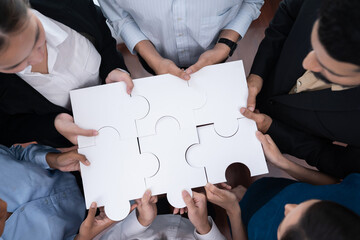 Diverse corporate officer workers collaborate in office, connecting puzzle pieces to represent...