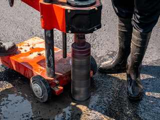 asphalt road being drilled using a core drill machine
