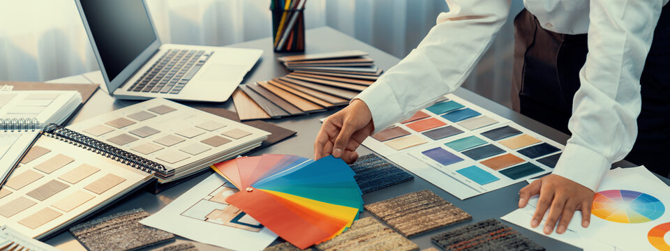Interior architect designer at workstation table choosing various color samples art tool design with home blueprint. Creative color selection for house renovation or design concept. Insight