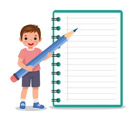 Little boy student holding big pencil standing beside big notebook