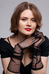 Fototapeta premium An alluring woman, adorned in a striking black dress and vivid red lips, emanates timeless elegance. This image is well-suited for fashion and beauty campaigns, showcasing sophistication and style.