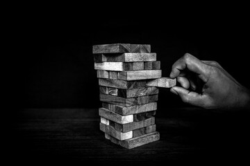 Hand placing wooden block tower stack in pyramid stair step with caution to prevent collapse or...