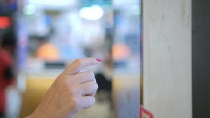 Girl using touch terminal makes a quick order through the self-service. Woman choosing dessert via self-service machine at fast food restaurant. Person swipes the screen making an order.