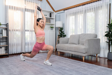 Fototapeta na wymiar Vigorous energetic woman doing yoga and weight lifting exercise at home. Young athletic asian woman strength and endurance training session as home workout routine.