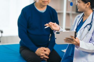 Elderly man engages in thoughtful discussion with compassionate asian people female doctor, addressing health agenda and medical concerns, exemplifying importance of patient-centered care.