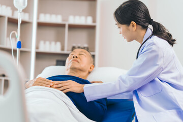 Caring female doctor provides attentive medical care to asian people elderly man lying in hospital bed, highlighting importance of expert healthcare and support during times of illness.