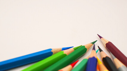 Border of an assortment of colourful pencils on white background