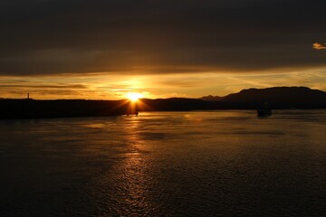 Sunset silhouettes Canadian islands and sun glitter reflects off the water on the Inside Passage