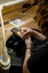 unrecognizable woman grinding ring in jewelry atelier