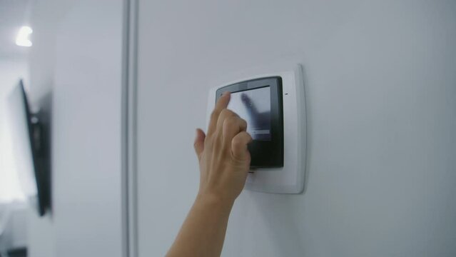 Close up of medical worker entering password on electronic smart monitor hanging on the wall. Nurse uses sensor thermostat or pressure controls in hospital ward. Modern clinic or medical facility.