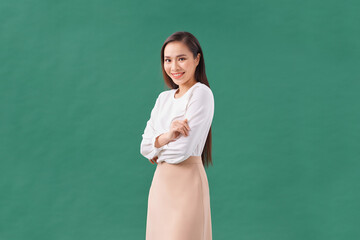 Portrait of a happy woman standing with arms folded isolated on a green background