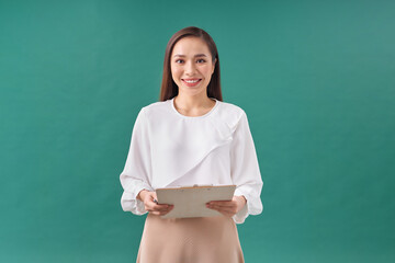 Portrait of a happy asian businesswoman holding clipboard isolated over green background