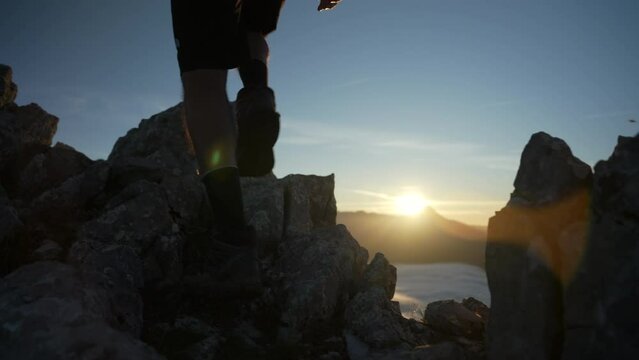 A mountaineer ascends to the top of the mountain step by step with the sun in the background backlit in a beautiful sunrise enjoying the first hours of light of a summer day in the Pyrenees