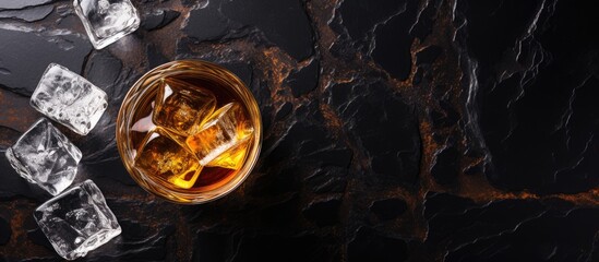 Top view of whiskey on stone table with ice and space for text