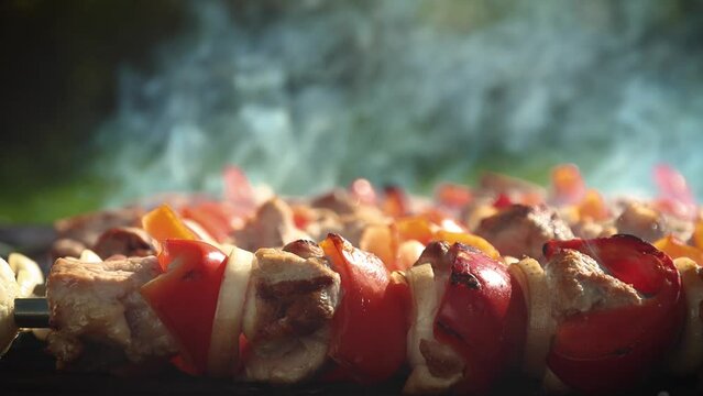 Close up shashlik dish on charcoal barbeque grill. Food preparation process of  marinated pork meat and red sweet pepper on skewers.