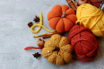 Knitted pumpkin, woolen threads and spices on a gray background with space for text. Handmade Halloween decorations. 