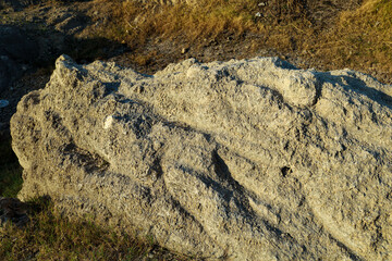 Large Rock Sitting on Top of a Grassy Field. Mossy Boulder in a Meadow. Limestone mining on Mount Beko. limestone dragon head silhouette