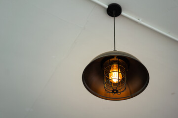 A retro style metallic ceiling lighting lamp is glowing in warm light shade. Interior furniture for...