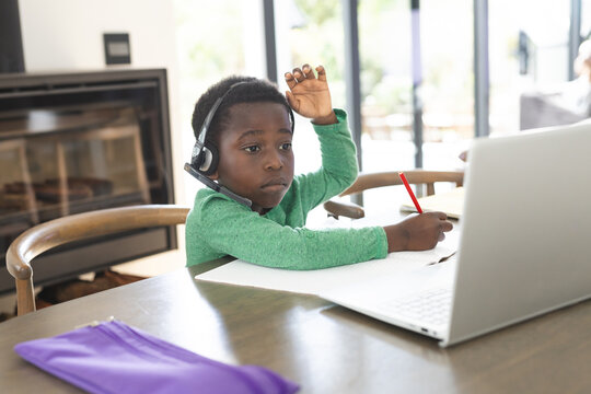 African american boy having online class using headphones and laptop with copy space, slow motion