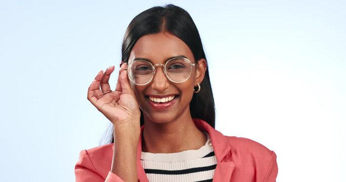 Fashion, face and wink by woman with glasses in studio for clothes or promotion on blue background. Flirt, portrait and Indian female model with cool frame choice, outfit or trendy style or good mood