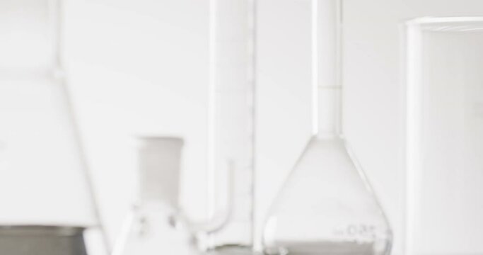 Video of close up of glass laboratory beakers and dishes with copy space on white background