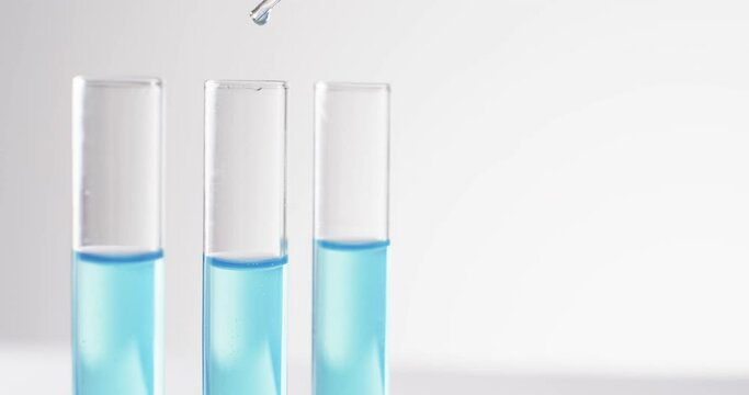 Video of glass laboratory test tubes and pipette with blue liquid and copy space on white background