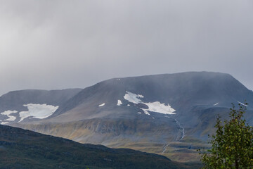 Great mountain view on cloudy weather. Melting snow creating river streaming down to valley. Lyngen Alps.