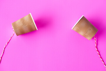 DIY paper cups with string on pink background. Concept, telephone toys which apply with science knowledge about vibration sound through straining strings causing us to hear the sound.   