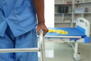 Physical therapist helps a male patient use a walker to practice walking. Support yourself from recovery from sore legs and ankles. Physical therapy service concept.