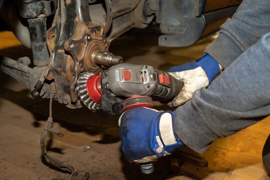 The car mechanic cleans, derusts and maintains the wheel hub bearing in the workshop. Protective gloves. Working.