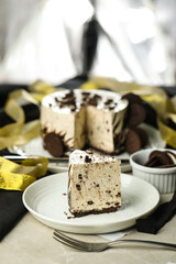 Oreo Cheesecake slice include chocolate, cream, sugar with fork and flowers served in plate isolated on napkin side view of cafe food