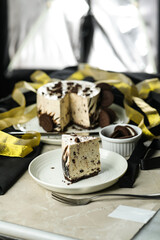 Oreo Cheesecake slice include chocolate, cream, sugar with fork and flowers served in plate isolated on napkin side view of cafe food
