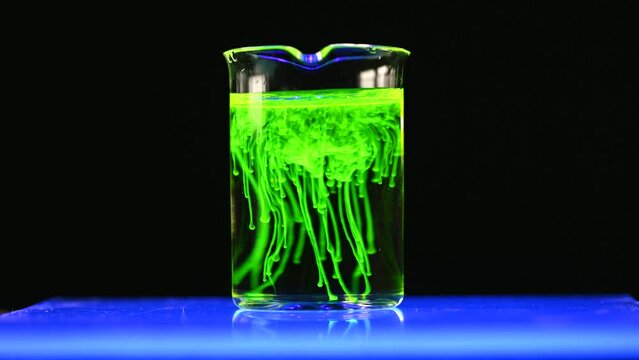 Fluorescent toxic substance dissolving in the chemical solution. The scientist conducts demonstration experiments with solutions. The phenomenon of brownian motion fluorescence.