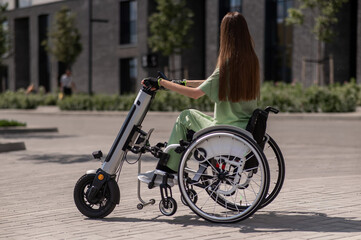 A woman in a wheelchair with an assistive device for manual control. Electric handbike. 